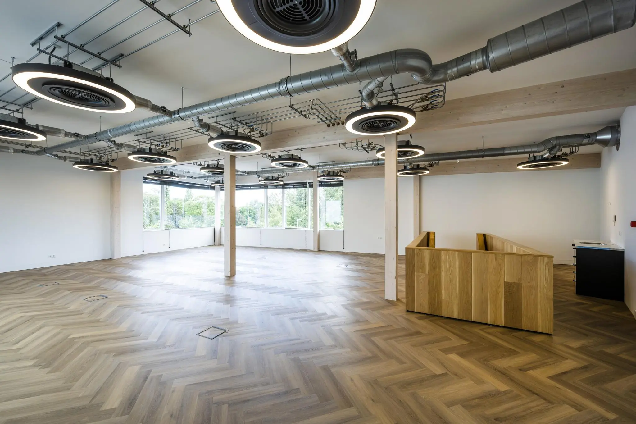 Moderne lege kantoorruimte aan de Fred. Roeskestraat met visgraatvloer, grote ramen en industriële plafondlampen.